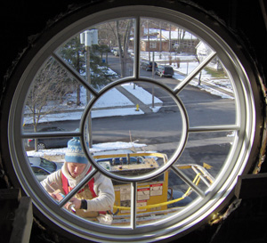 Round wood window sash being installed in church tower.